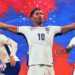 A blue and red graphic overlaid with Lewis Hall, Jude Bellingham and Reece James in white England shirts