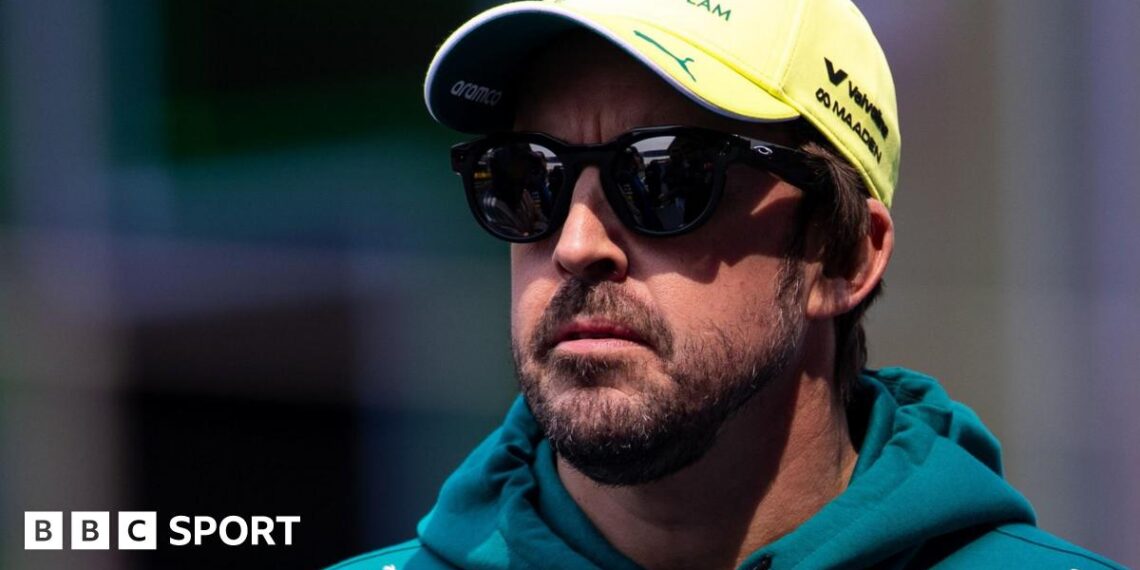 Fernando Alonso wearing sunglasses, an Aston Martin hoodie and a yellow cap