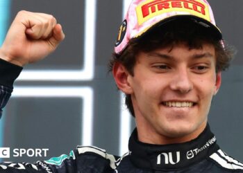 Kimi Antonelli smiles and clenches his fist in celebration on the podium after winning the Japanese Grand Prix