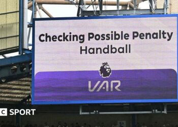 A big screen display a VAR check for a possible penalty during a Premier League match