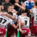 Wakefield's Tom Johnstone diving towards the line to score a try one-handed for his side under pressure from two Wigan defenders in the corner.