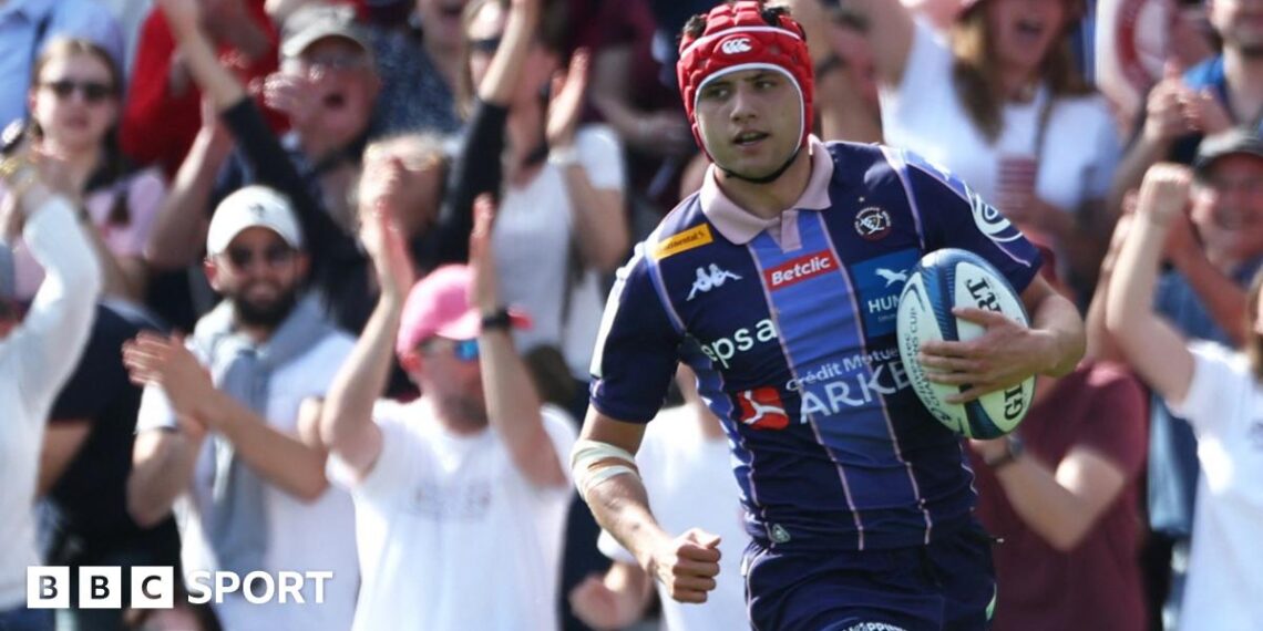 Louis Bielle-Biarrey with the ball in his left hand while wearing Bordeaux's dark and light blue striped shirt in match action