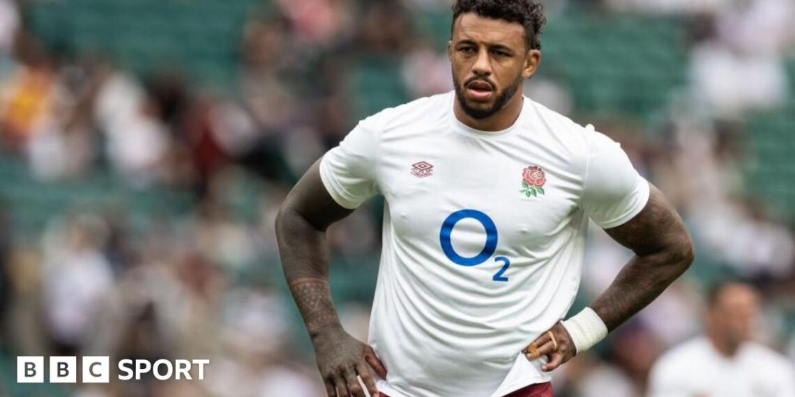 Courtney Lawes standing on the pitch with an England shirt on and his hands on his hips