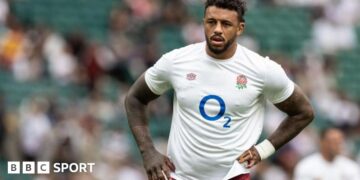 Courtney Lawes standing on the pitch with an England shirt on and his hands on his hips