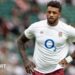 Courtney Lawes standing on the pitch with an England shirt on and his hands on his hips