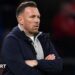 Craig Bellamy, in an open dark jacket with a grey top underneath, looks on with a focused stare during Wales' match against Northern Ireland
