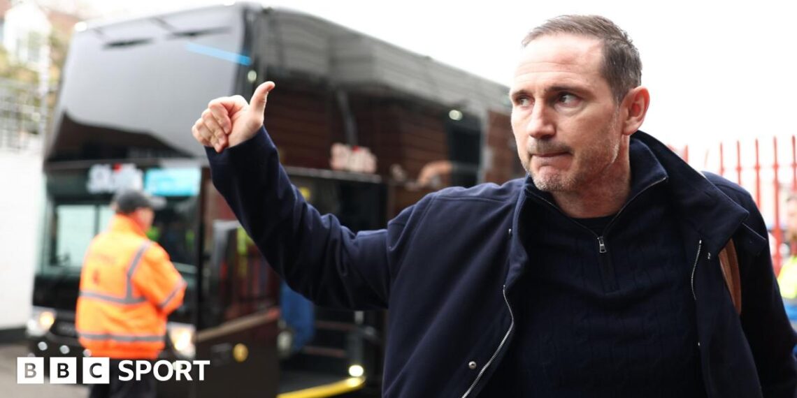 Frank Lampard gives a thumbs up in the direction of a bus outside a stadium.
