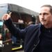 Frank Lampard gives a thumbs up in the direction of a bus outside a stadium.