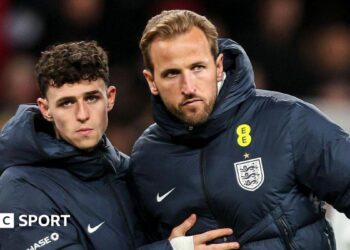 Phil Foden and Harry Kane in England blue coats after the defeat by Japan, with both players stern-faced