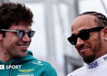 Aston Martin driver Lance Stroll and Ferrari driver Lewis Hamilton smiling while in conversation at the 2026 Australian Grand Prix. Both men are wearing sunglasses