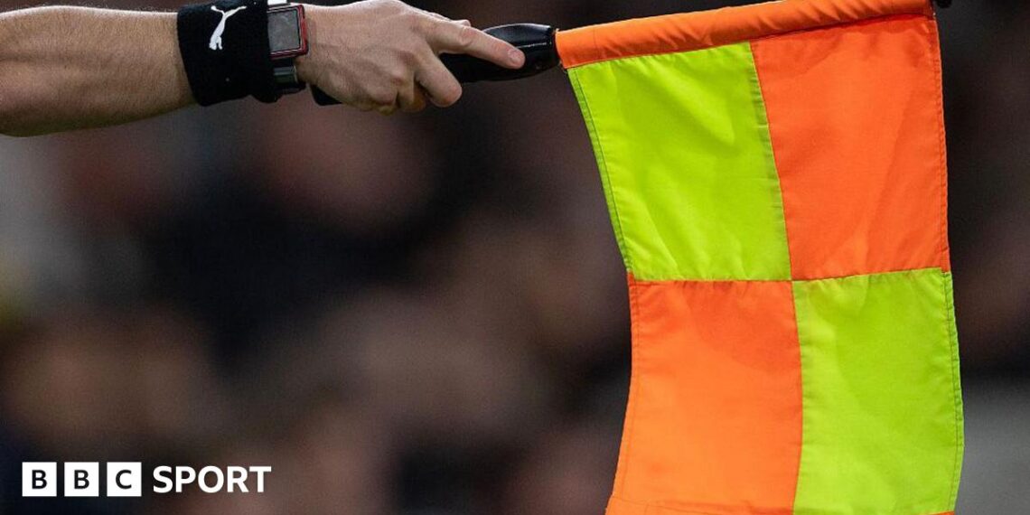 An assistant referee holds out a flag for offside