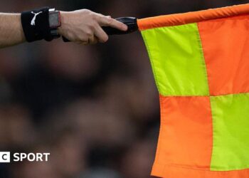 An assistant referee holds out a flag for offside