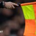 An assistant referee holds out a flag for offside