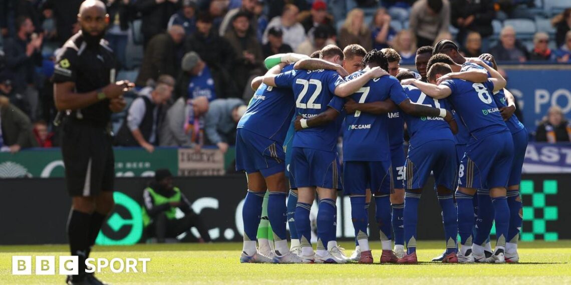 Gary Rowett, wearing a black tracksuit with Leicester branding, looks dejected on the pitch after a defeat