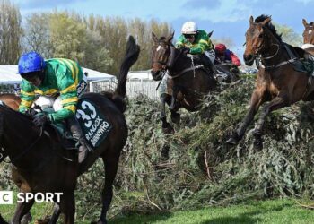 Horses jump one of the Grand National fences in the 2026 race