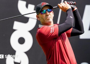 Sergio Garica tees off during a LIV Golf tournament with the branding in the background