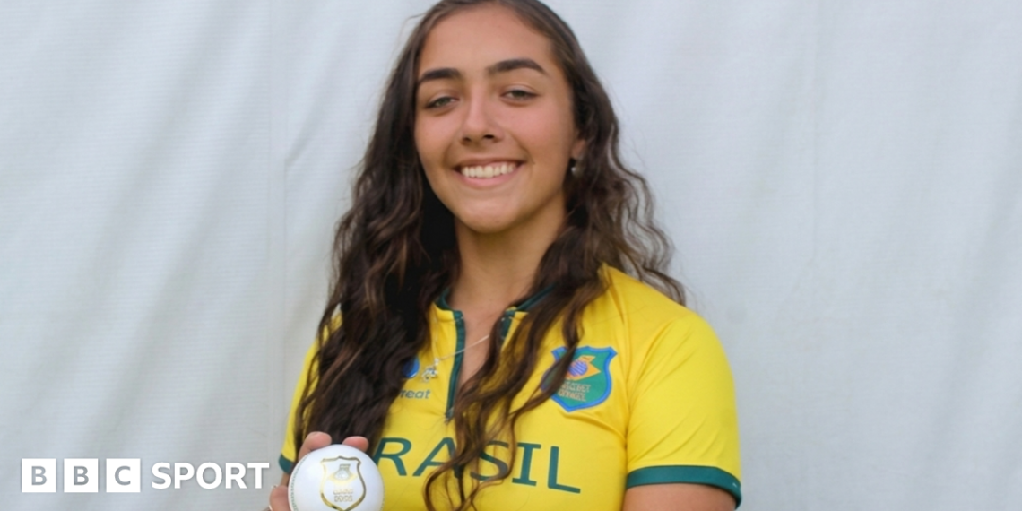 Laura Cardoso holding a white ball while wearing a Brazil cricket kit