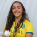 Laura Cardoso holding a white ball while wearing a Brazil cricket kit