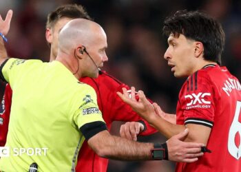 Referee Paul Tierney speaks with Lisandro Martinez of Manchester United after showing him a red card for pulling the hair of Dominic Calvert-Lewin of Leeds United
