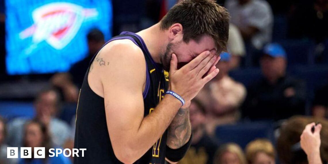 LA Lakers star Luka Doncic covers his face with his hands as he walks off the court after suffering an injury