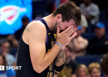 LA Lakers star Luka Doncic covers his face with his hands as he walks off the court after suffering an injury