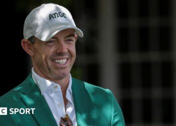 Rory McIlroy smiles as he talks to Augusta officials on his return to the Masters