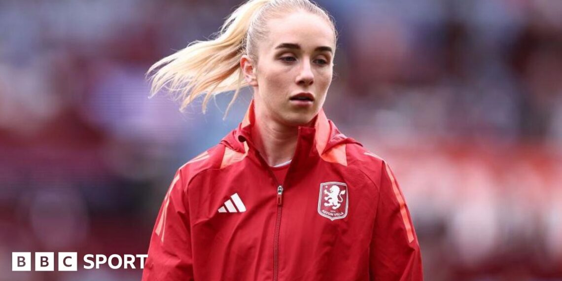 Missy Bo Kearns wearing a red jacket with an Aston Villa badge on the chest