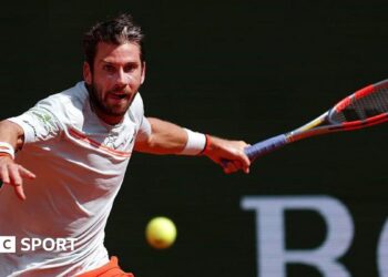 Cameron Norrie, in largely white T-shirt with orange trim, plays a forehand at the Monte Carlo Masters on Sunday