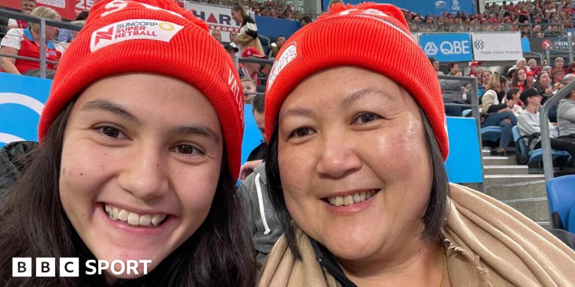Sophie Fawns with her mother, Maureen, both smiling and wearing NSW Swifts red woolly hats