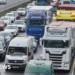 People walk with luggage past heavy traffic on Dublin's M50