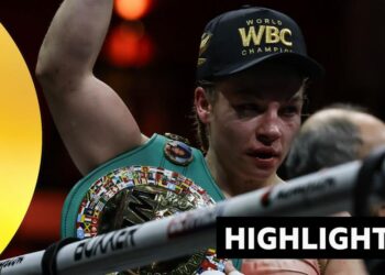 Lauren Price face is bruised after beating Stephanie Pineiro. She holds arm up and wears a WBC champion cap.
