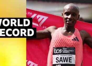 Sebastian Sawe holds up red flag behind his back after winning the 2026 London Marathon