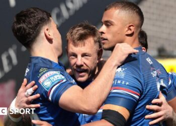 Tom Johnstone is surrounded by team-mates, all in Wakefield Trinity blue, as they celebrate one of his three tries against Bradford Bulls.