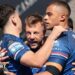 Tom Johnstone is surrounded by team-mates, all in Wakefield Trinity blue, as they celebrate one of his three tries against Bradford Bulls.