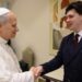 The Pope, wearing white shakes hands with Harry Clark, who is wearing a black suit.