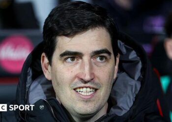 Bournemouth manager Andoni Iraola smiles as he watches a match