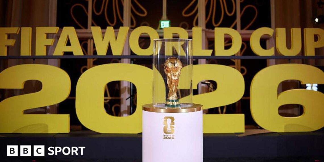 The World Cup on display on a white stand prior to the draw in December in Washington with Fifa World Cup 2026 in big gold letters in the background.