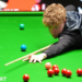 Stan Moody stretches over the snooker table to play a shot