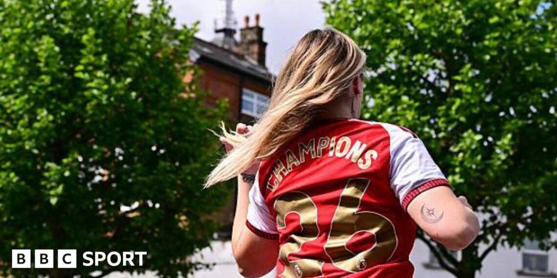 Female Arsenal fan with 'Champions 26' on the back of her shirt