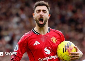 Bruno Fernandes celebrates a goal for Manchester United, with his mouth wide open and the ball in his left hand