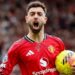 Bruno Fernandes celebrates a goal for Manchester United, with his mouth wide open and the ball in his left hand