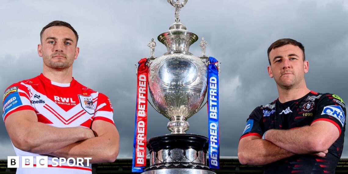 St Helens' Matty Lees and Wigan Warriors' Harry Smith stand alongside the Challenge Cup trophy