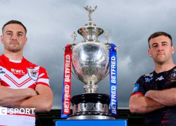 St Helens' Matty Lees and Wigan Warriors' Harry Smith stand alongside the Challenge Cup trophy