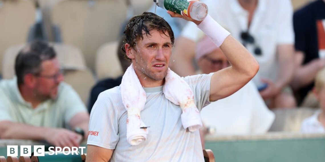 Casper Ruud pours water over his head during a change of ends