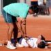 Jakub Mensik lies on the floor and opponent Mariano Navone tries to assist him