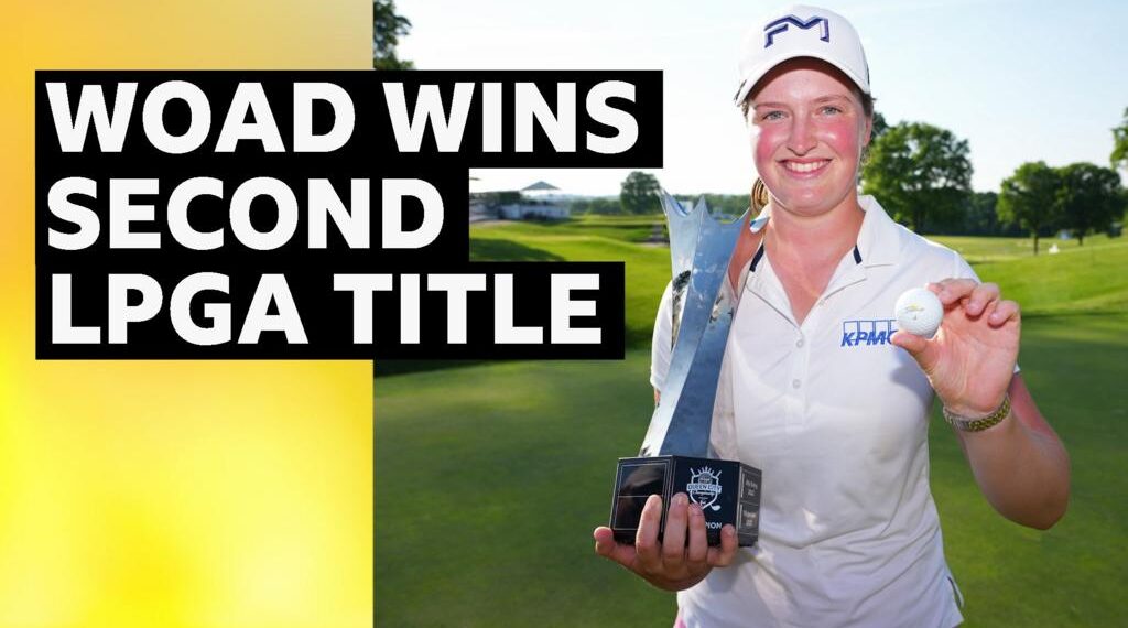Lottie Woad smiles and holds up a silver trophy Krigor Queen's City Championship trophy in one hand, and a golf ball in her other hand