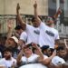Bordeaux Begles players celebrate last year's Champions Cup victory at an event in the city, lifting the large trophy as a flag-waving crowd stand behind them. The players wear white T-shirts with the slogan WE ARE CHAMPIONS