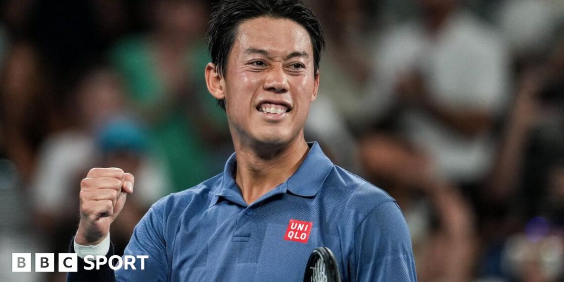 Japan player Kei Nishikori, in a blue polo shirt, pumps his fist on a tennis court, blurred crowd behind him