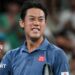 Japan player Kei Nishikori, in a blue polo shirt, pumps his fist on a tennis court, blurred crowd behind him