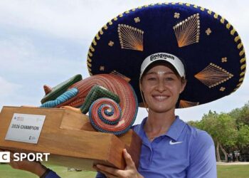 Nelly Korda celebrates winning the Riviera Maya Open in Mexico, wearing a traditional large Mexican hat and blue golf shirt, smiling, and holding a colourful trophy